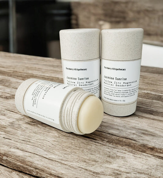 Two deodorant containers on a wooden surface with 'Raspberry Hill Apothecary' branding.