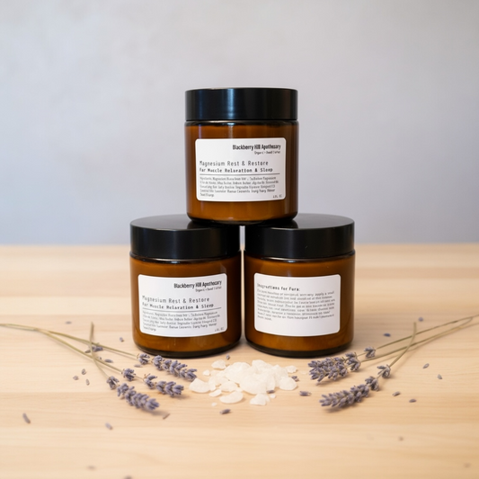 Three amber jars with black lids on a wooden surface with lavender flowers.