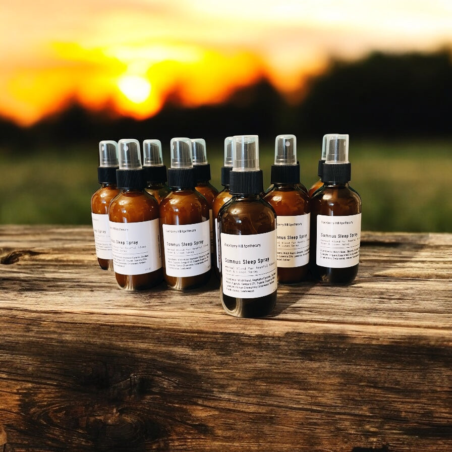 Row of brown spray bottles with labels on a wooden surface against a sunset background