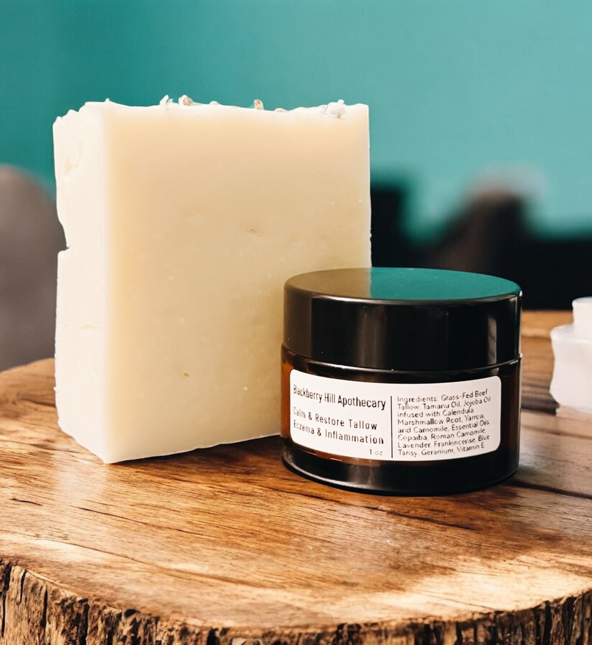 Bar of soap and jar with label on a wooden surface against a teal background