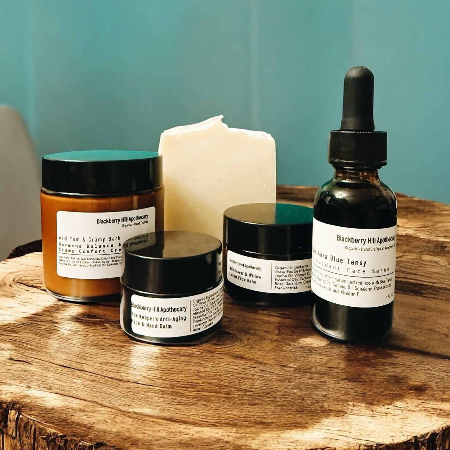 Collection of Blackberry Hill Apothecary skincare products on a wooden surface with a teal background.