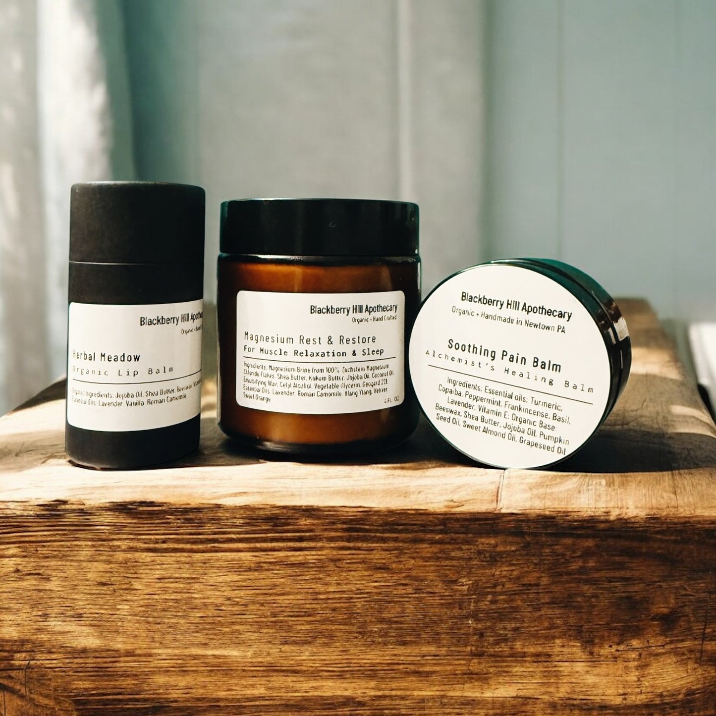 Three skincare products from Backberry Hill Apothecary on a wooden surface.